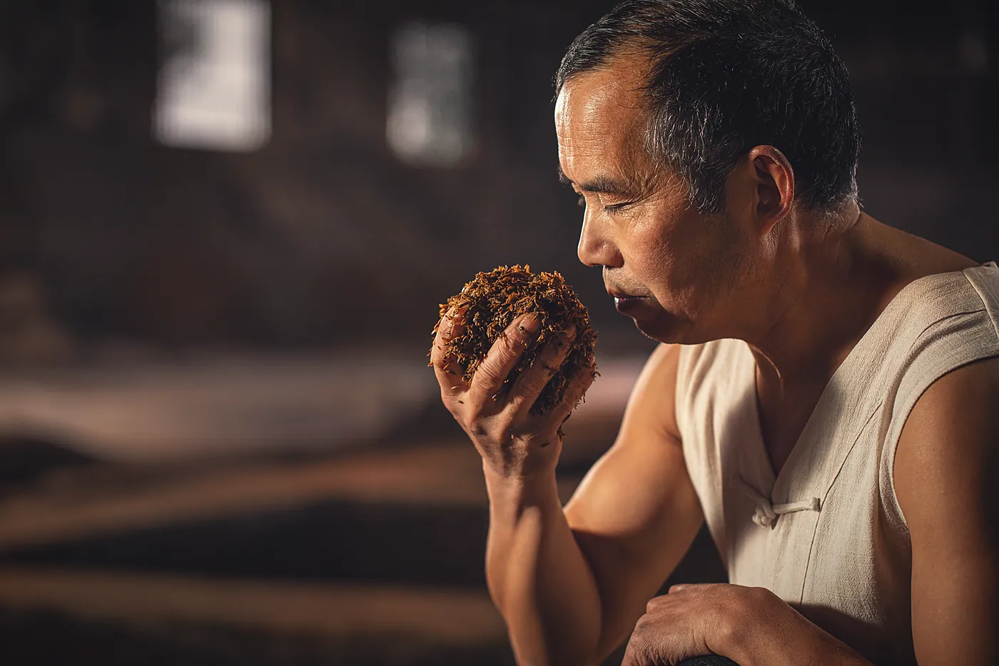 A distiller smelling fermented grain