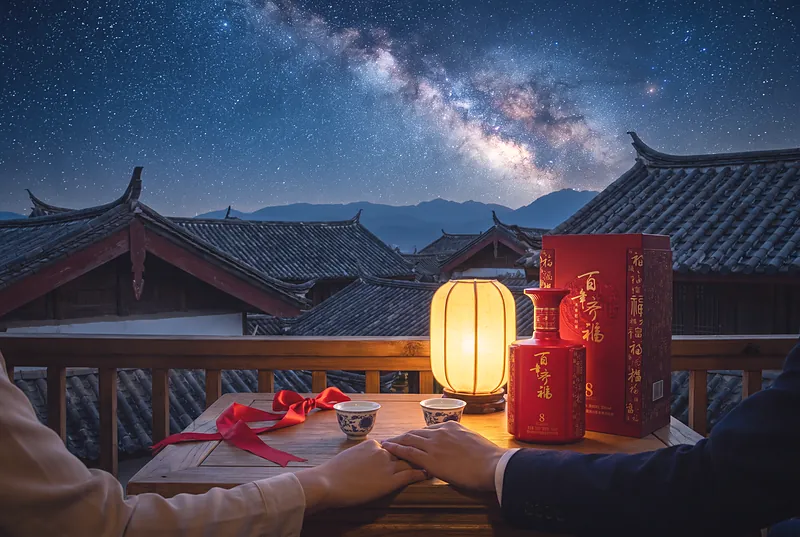 A couple's hands on a balcony table at night with two small cups and a red silk ribbon, under the Milky Way above Chinese rooftops