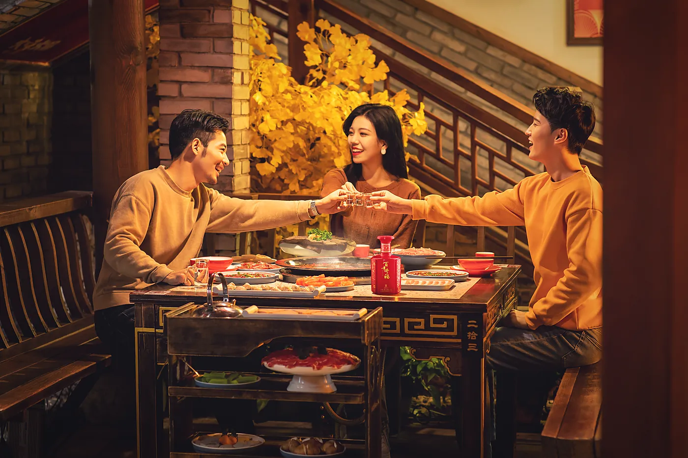 Friends raising small cups of baijiu together at a banquet table