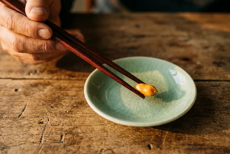 A pair of chopsticks picking up a roasted peanut