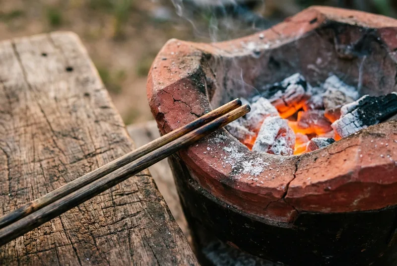 Glowing charcoal embers inside a traditional red clay stove
