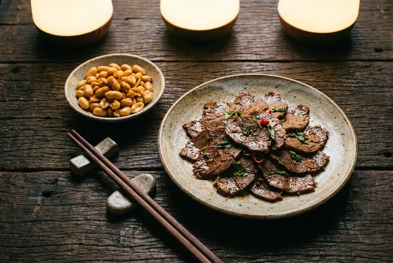 A close-up of sliced spiced beef and fried peanuts on a table